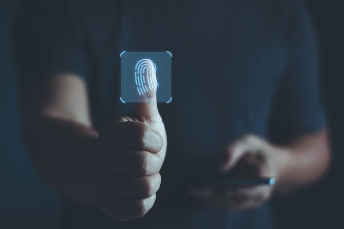 A person pressing their thumb onto a glowing fingerprint icon