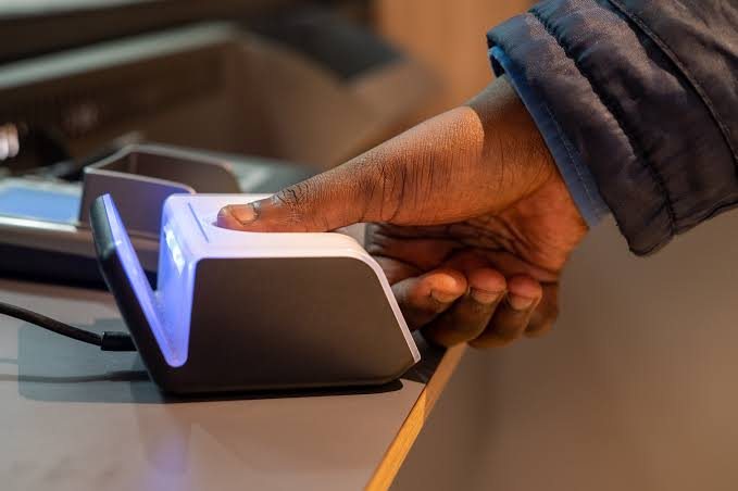 A hand resting a finger on a fingerprint reader at a service counter